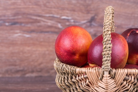 Fresh peaches in a basket on a wooden backgroundの写真素材