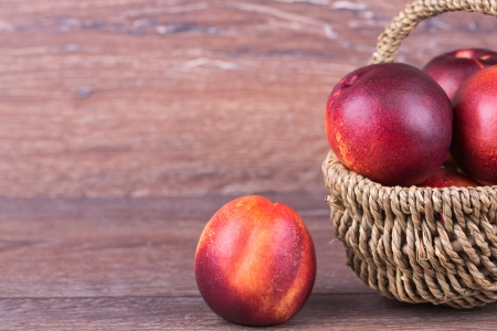 Fresh peaches in a basket on a wooden backgroundの写真素材
