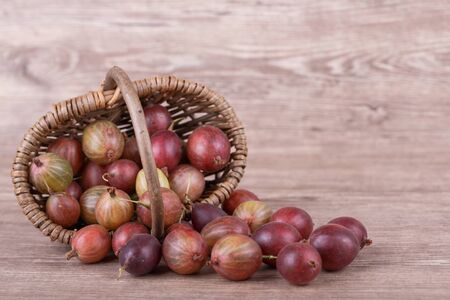 Ripe gooseberries in a basket on a wooden backgroundの写真素材