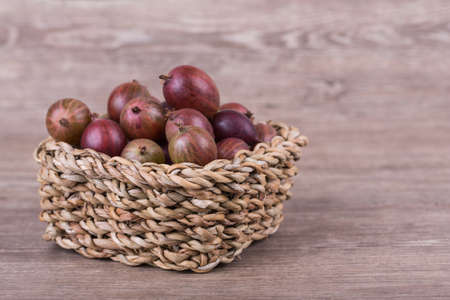 Ripe gooseberries in a basket on a wooden backgroundの写真素材