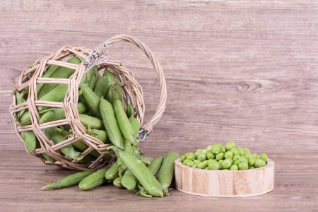 peas in a basket on a wooden backgroundの写真素材