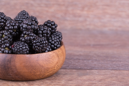 blackberries in wooden bowl on white backgroundの写真素材
