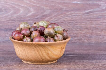 gooseberries in a wooden bowl on a wooden backgroundの写真素材