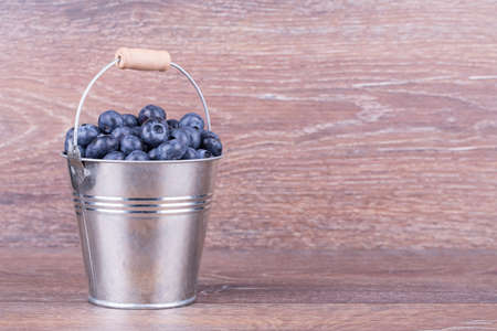 blueberries in a bucket on a wooden backgroundの写真素材