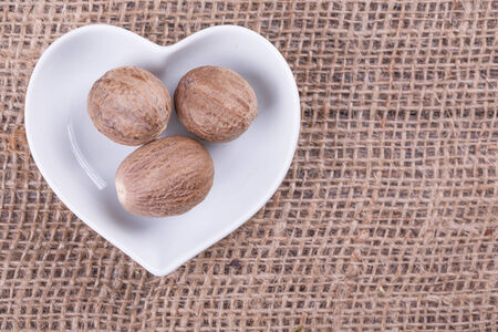 Nutmeg in  cup in the shape of heart on sack  cloth