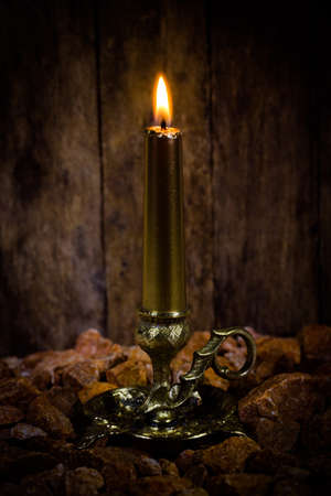 candle in candlestick on old wooden background