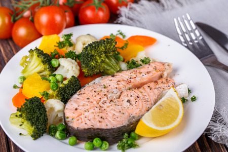 Steamed salmon with vegetables on  plate on wooden backgroundの写真素材