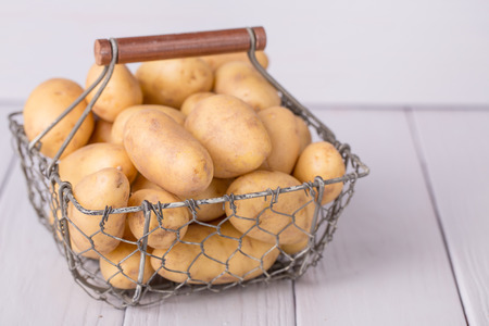 potatoes in the basket on wooden backgroundの写真素材