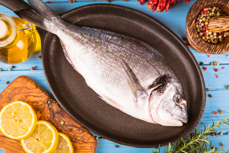 Fresh fish dorado with vegetables on wooden backgroundの写真素材