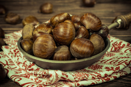 chestnuts in a pan on a wooden backgroundの写真素材