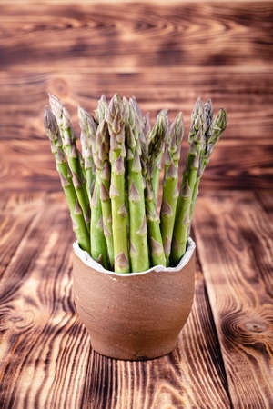 Asparagus in earthen bowl on rustic wooden backgroundの写真素材