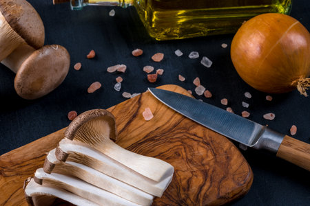 Fresh raw king, royal oyster mushrooms on dark wooden table, sliced, preparation, top viewの写真素材