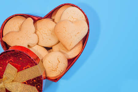 Beautiful holiday box in the shape of a heart with biscuits for a gift for Valentine's Day on a blue background.の写真素材