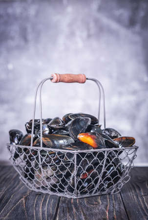 Fresh Mussels in a Basket on a wooden board. Seafood. Dark backgroundの写真素材