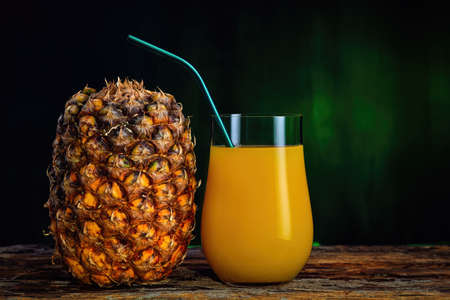 Fresh pineapple juice in a glass and fresh pineapple on a dark green background.の写真素材