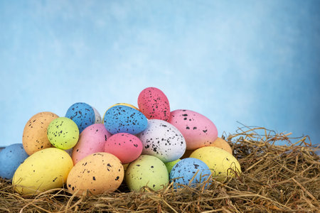 Colorful easter eggs on dry grass on sky blue background