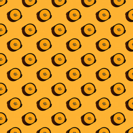Repeating bowl of pumpkin puree soup on orange background