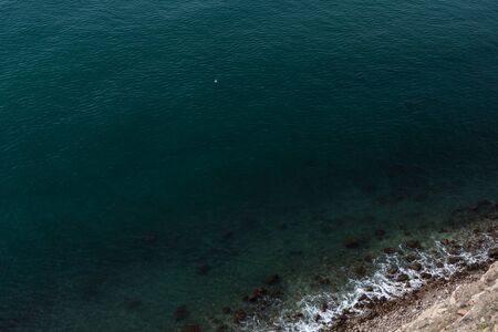 sea ââwave washes yellow beach of pebbles, sea occupies a large area of ââthe picture is in the corner of coastの写真素材