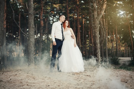 Wedding day. The groom embraces the bride, loving couple in a pine forest. Woman tenderly hugging...