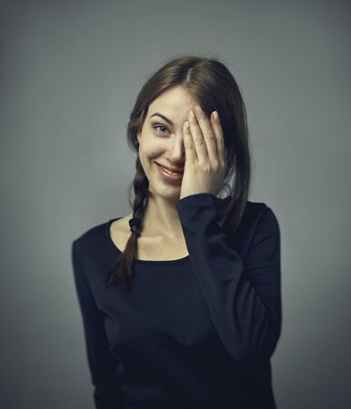 Headshot of cute attractive young European female covering open mouth with hand and closing eyes....