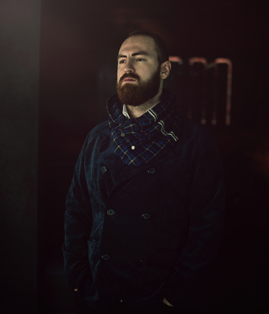 Handsome bearded man hipster with stylish beard in white shirt and chekered scarf standing with serious face in beauty salon or barbershopの写真素材