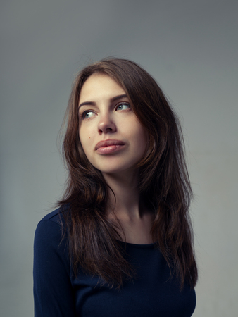 Beautiful woman with full lips in a black dress over gray background in studioの写真素材