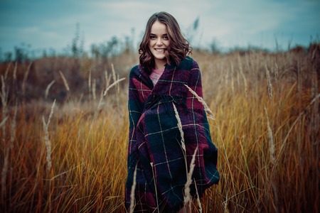 Girl walking in the park. Girl wearing plaid. Pretty woman in the forest. Cold weatherの写真素材