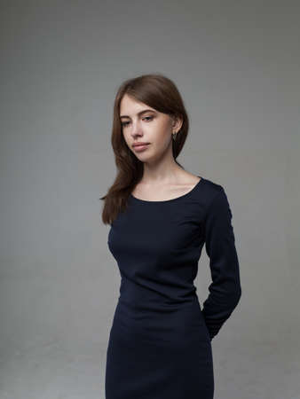 Beautiful woman with full lips in a black dress over gray background in studioの写真素材