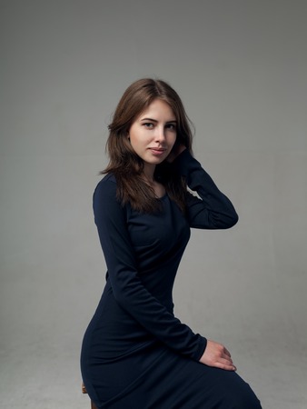 Beautiful woman with full lips in a black dress over gray background in studioの写真素材
