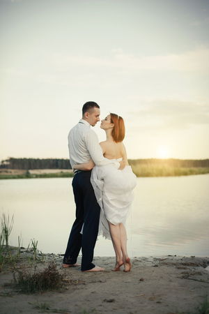 Elegant gentle stylish groom and bride near river. Wedding couple in loveの写真素材