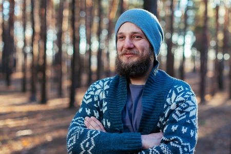 portrait of hipster man with beard and mustache in the woods forest. Dressed in the grey jamper and hatの写真素材