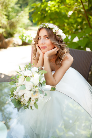 a young bride sits at a glass table with her hands folded at the chin. Boredの写真素材