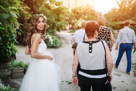 the bride goes to the guests in a white dress and smilingの写真素材