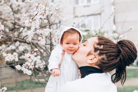 Little baby with her young mother in the blossoming Spring gardenの写真素材