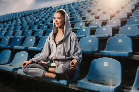 Young attractive woman practicing yoga, sitting in Padmasana exercise, Lotus pose on meditation session, working out wearing sportswear on the stadiumの写真素材