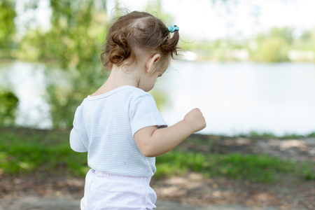 Portrait of cute little Caucasian girl wearing white walking at river in summerの写真素材