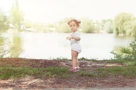 Portrait of cute little Caucasian girl wearing white walking at river in summerの写真素材