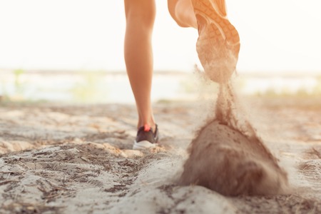 Close up of the legs of a young woman who is running off road in a park on sand Health life conceptの写真素材