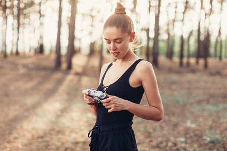 Hipster girl with using vintage photo camera close up, copy space of blank empty mockup, view tourist holding in hands and photograph on device travel on background pine forestの写真素材