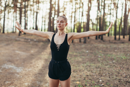 Stretching athlete warming up for a workout outdoors. healthy fitness lifestyle Pine forest on the backgroundの写真素材