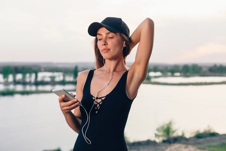 Wireless earbuds running woman on fitness workout. Active lifestyle athlete listening to smartphone music phone app with in-ear gear on beach. Weight loss conceptの写真素材