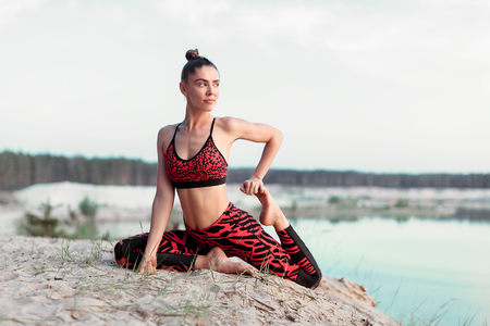 An attractive young woman doing a yoga pose for balance and stretching near the lake high in the mountains Health life conceptの写真素材