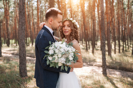 Sunshine portrait of happy bride and groom outdoor in nature location at sunset. Warm summertime.の写真素材