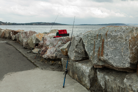 Two fishing rods sticking out of stones, on the beach in Morgat France 29 May 2018.の写真素材
