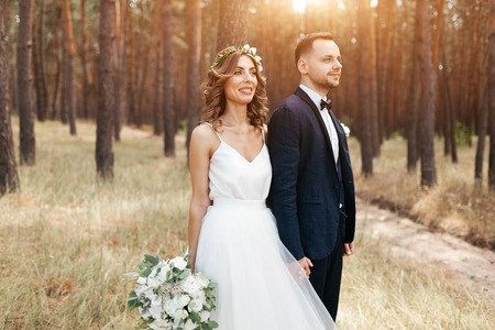 Bride and groom at wedding Day walking Outdoors on summer nature. Bridal couple, Happy Newlywed woman and man embracing in green park. Loving wedding couple outdoor.の写真素材