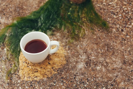 cup of coffee on the sea water and stone background. Sea freshness morning concept.の写真素材