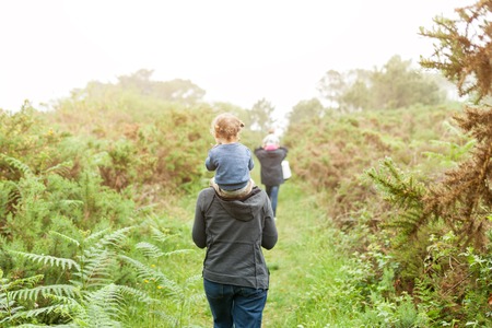 happy family at sunset. mother and daughter having fun and playing in nature. the child sits on the shoulders of his parent. Traveling with little child Hiking on the forest background.の写真素材
