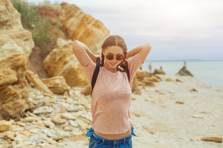 A hipster girl with braided hair in pigtails is walking along the beach in clothes. Summer concept, leisure tourism.の写真素材