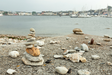 Stones pyramid on pebble beach symbolizing stability, zen, harmony, balance. Shallow depth of field with city on the backgroundの写真素材