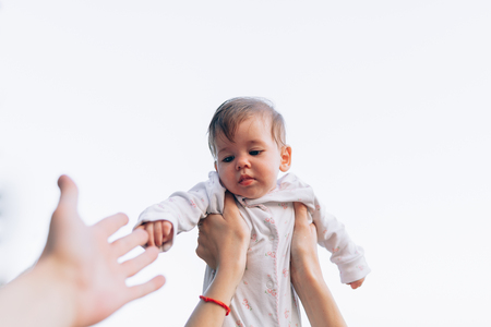 mother reach hand lift up play and show throws cute happy baby on sky at morning time. enjoy parenting emotion and good feeling family. smart generation peopleの写真素材